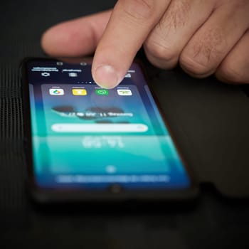 Fingers of a person operate a smartphone lying on the table