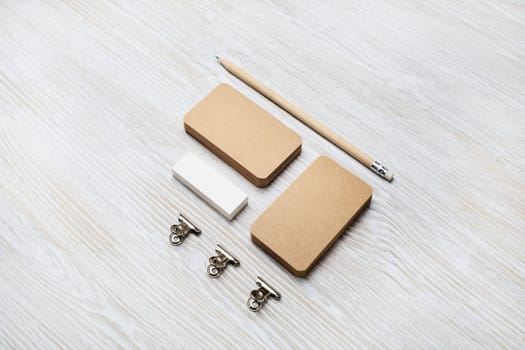 Blank kraft business cards, pencil and eraser on light wood table background. Branding mock up.