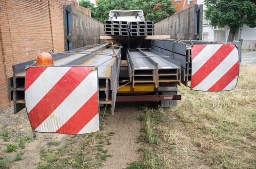 Building materials truck loaded with steel beams. Oversize load length restrictions concept