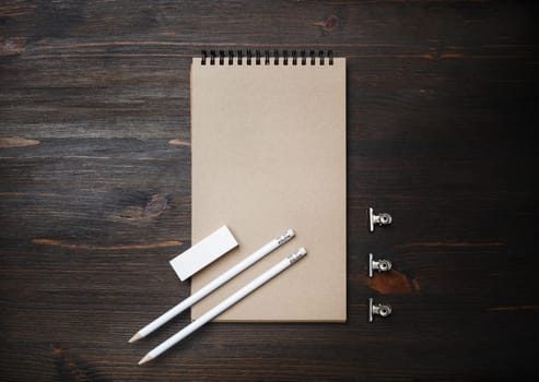 Blank black kraft notebook, pencil and eraser on wooden background. Top view. Flat lay.