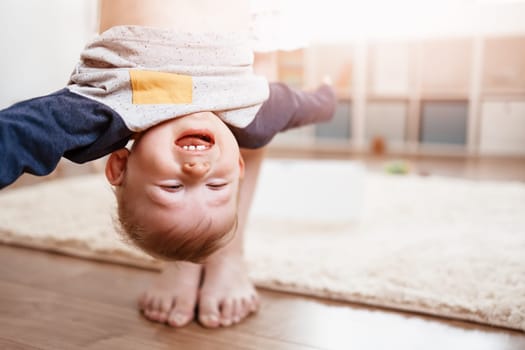 Mother holding upside down her laughing child. Concept of the family relationship and mother's love.