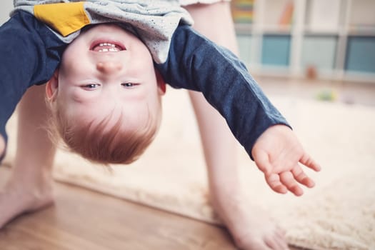 Mother holding upside down her laughing child. Concept of the family relationship and mother's love.