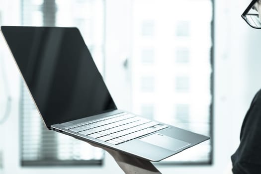 Young freelancer in black shirts holds up a very thin, elegant Ultrabook