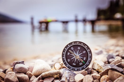 Close up of a nautical compass on the beach, coastline in the blurry background