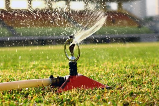 Water jets sprinkling stadium field.
