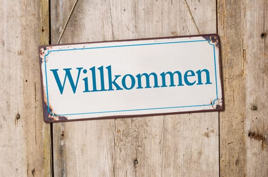 Old tin sign in front of rustic wooden wall - Welcome