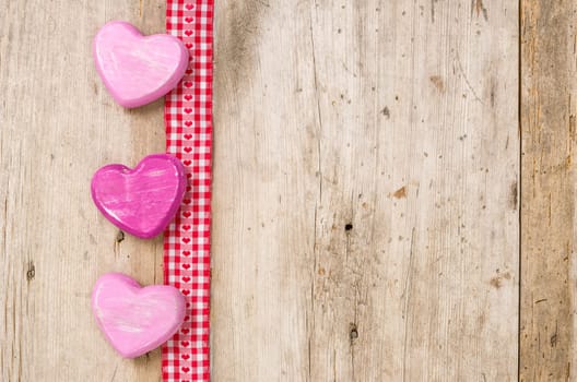 Gift ribbon with hearts in front of rustic wooden boards