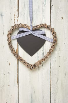 Braided heart with chalkboard in front of white wooden boards