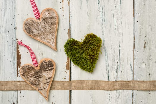 Hearts of bark and moss in front of white wooden boards