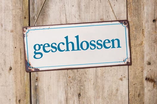 Old tin sign in front of rustic wooden wall - closed