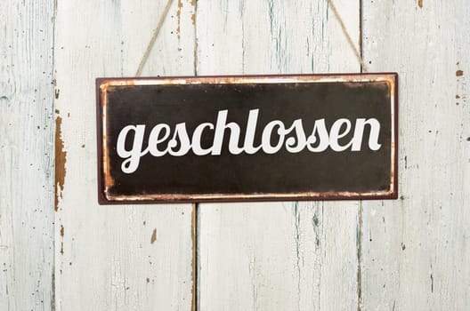 Old tin sign in front of white wooden wall - closed