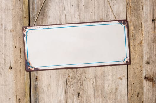 Empty tin sign in front of rustic wooden wall
