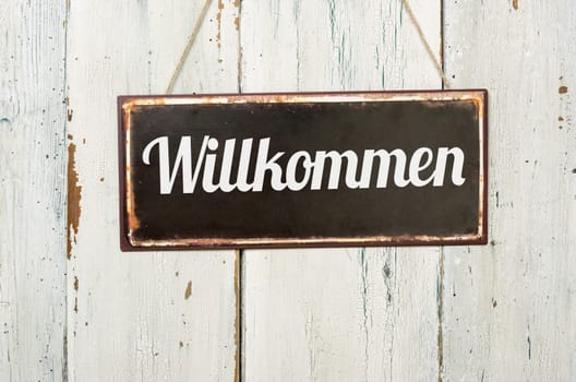 Old tin sign in front of white wooden wall - Welcome