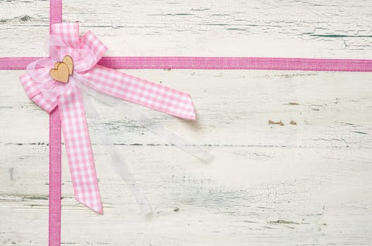 Pink gift ribbons with bow in front of white wooden boards