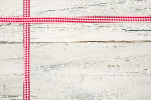 Red plaid gift ribbons in front of white wooden boards