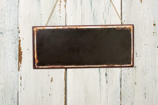 Empty tin sign in front of white wooden wall