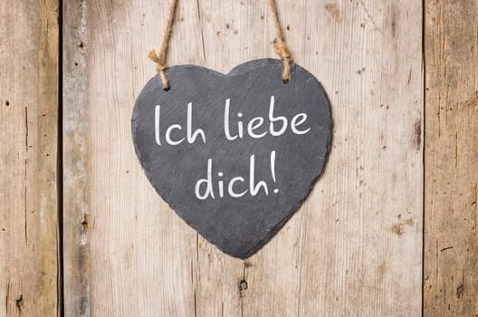 Heart board in front of rustic wooden wall - I love you