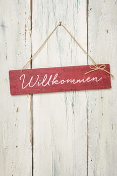 Red wooden sign in front of white wooden wall - Welcome