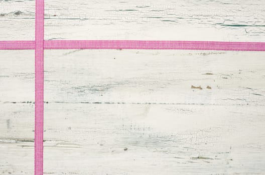 Pink gift ribbons in front of white wooden boards