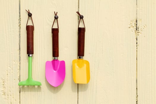 garden tools hang on wooden wall