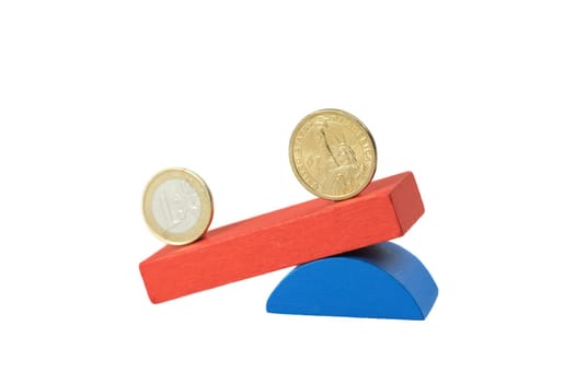 Euro coin and the US one dollar coin stand on the swing from wooden color blocks. Swing is on the side with the US dollar amount. Side view.