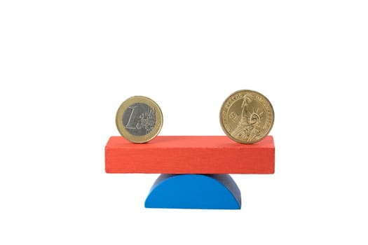 Euro coin and the US one dollar coin stand on the swing from wooden color blocks. Swing coin is in equilibrium
