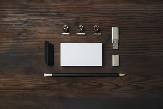 Blank stationery set. Blank business card, flash drive, pencil and eraser on wooden background. ID mockup. Responsive design template. Top view. Flat lay.