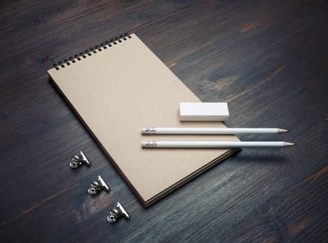 Photo of closed blank kraft notebook, pencil and eraser on wooden background. Stationery template.