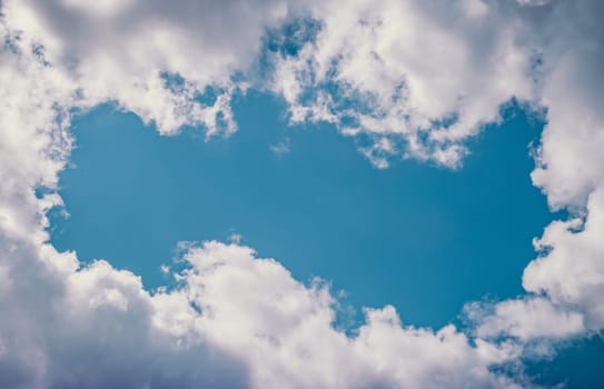 Blue sky background framed by white clouds, for text or title  placement