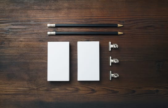 Blank stationery template on wood table background. Blank business cards, pencils and paper clips. Top view. Flat lay.