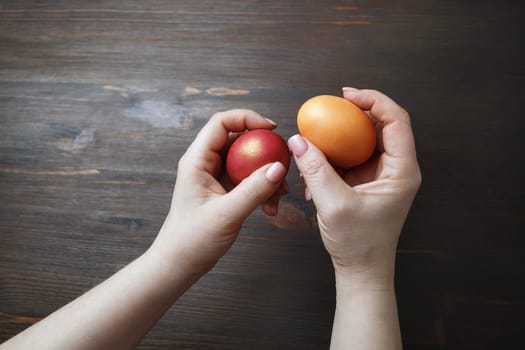 Easter eggs in female hands on wooden background.
