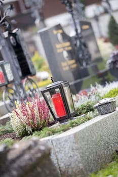 Candle in an iron lantern on a grave at a cemetery