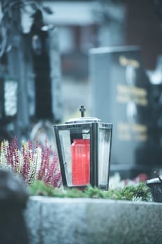 Candle in an iron lantern on a grave at a cemetery