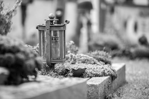 Candle in an iron lantern on a grave at a cemetery