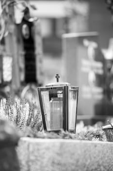 Candle in an iron lantern on a grave at a cemetery