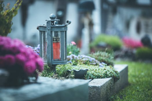 Candle in an iron lantern on a grave at a cemetery