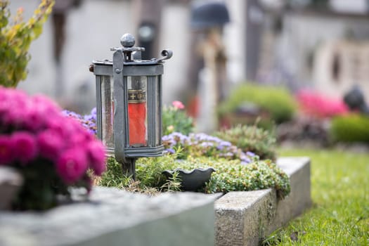Candle in an iron lantern on a grave at a cemetery