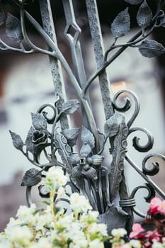 Iron sculpture on a grave at a cemetery, tombstone and flowers