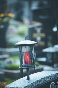 Candle in an iron lantern on a grave at a cemetery