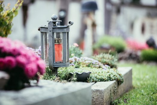Candle in an iron lantern on a grave at a cemetery