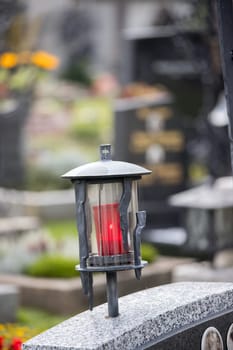 Candle in an iron lantern on a grave at a cemetery