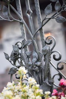 Iron sculpture on a grave at a cemetery, tombstone and flowers