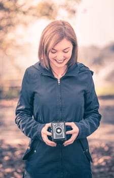 Cute girl is making pictures with a vintage camera, outside
