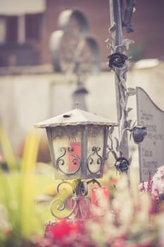 Candle in an iron lantern on a grave at a cemetery