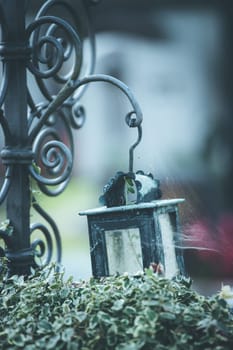 Candle in an iron lantern on a grave at a cemetery