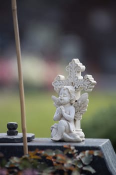 White angel on a grave at a cemetery, flowers