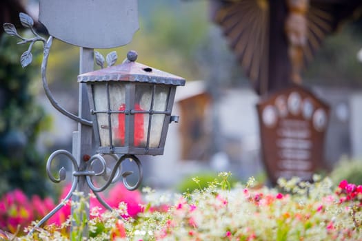 Candle in an iron lantern on a grave at a cemetery