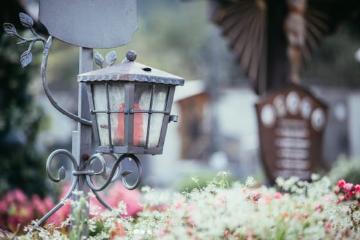 Candle in an iron lantern on a grave at a cemetery