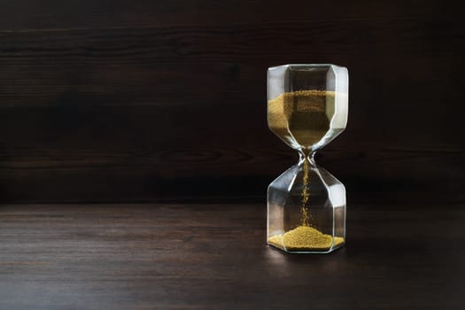 Hourglass on dark wooden background. Time concept.