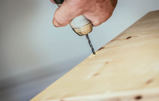 Craftsman is drilling in wood with drilling machine